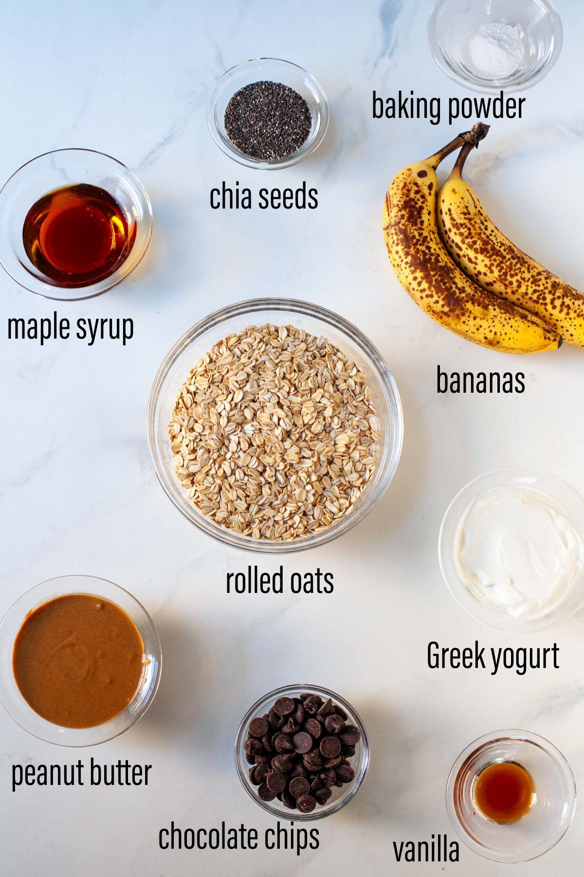 ingredients for peanut butter banana oat bars laid out in glass bowls on marble surface with text overlay