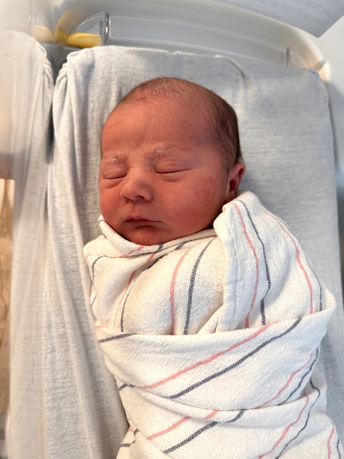 newborn baby boy in hospital blanket swaddle in bassinet