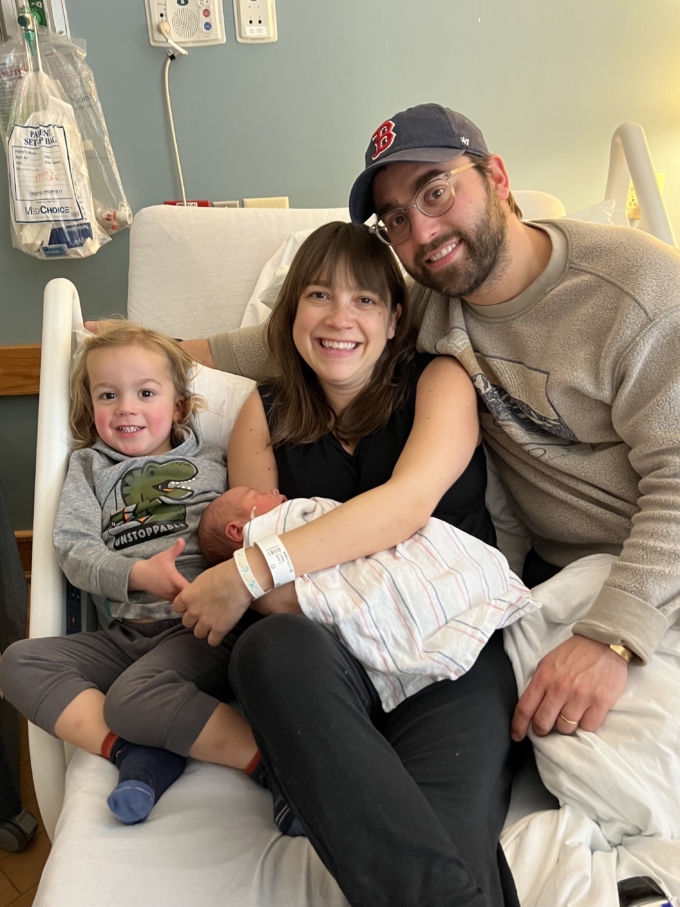 family of four posing in hospital bed after having baby